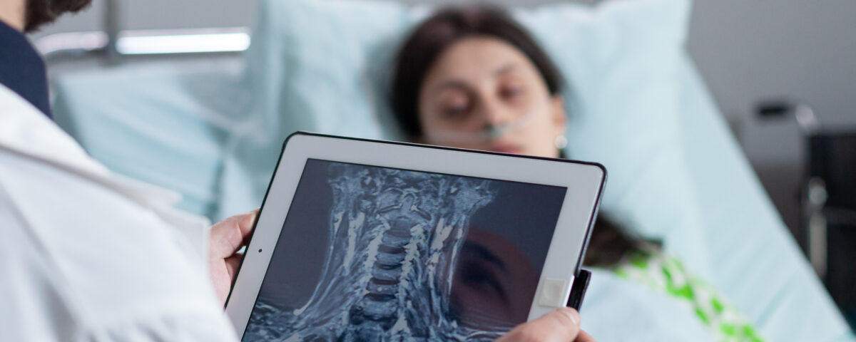 medic holding digital tablet with throat mri looking at sleeping patient in hospital bed e1700022743604