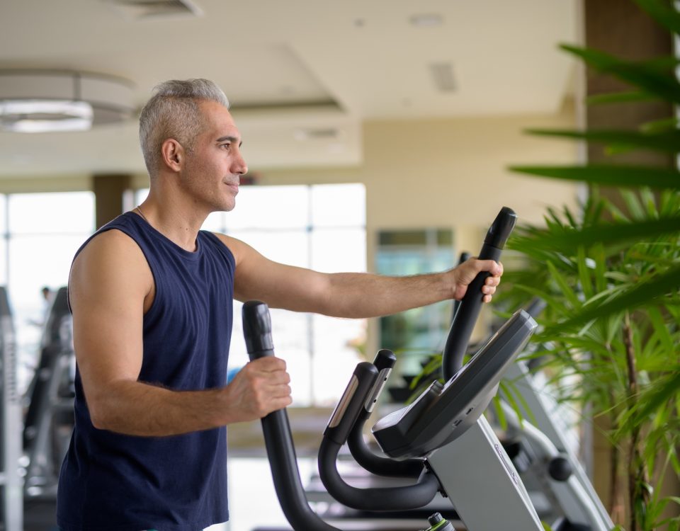 Hernie discale et activité physique : Ce qu'il faut savoir 16 Mature Persian man exercising with elliptical trainer machine at the gym